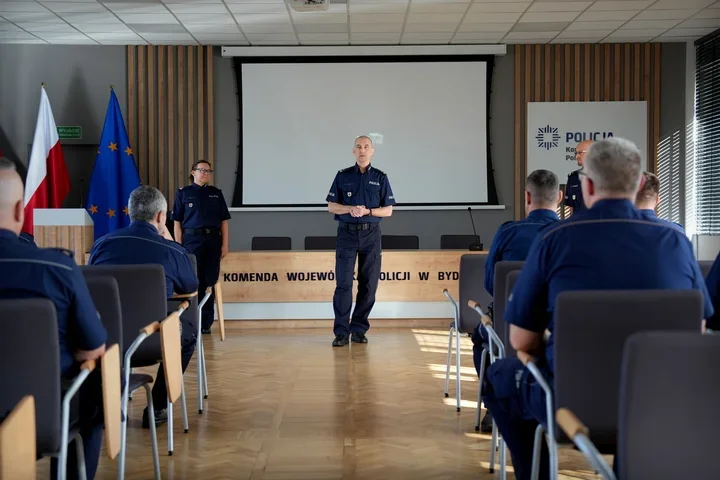 Funkcjonariusze policji w mundurach uczestniczą w spotkaniu w sali konferencyjnej Komendy Wojewódzkiej Policji w Bydgoszczy.
