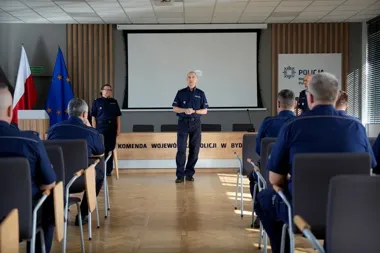 Funkcjonariusze policji w mundurach uczestniczą w spotkaniu w sali konferencyjnej Komendy Wojewódzkiej Policji w Bydgoszczy.