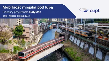 Pociągi metra i kolejki naziemnej przejeżdżają nad rzeką w gęsto zabudowanej dzielnicy tokijskiej, w tle most i wysokie budynki.
